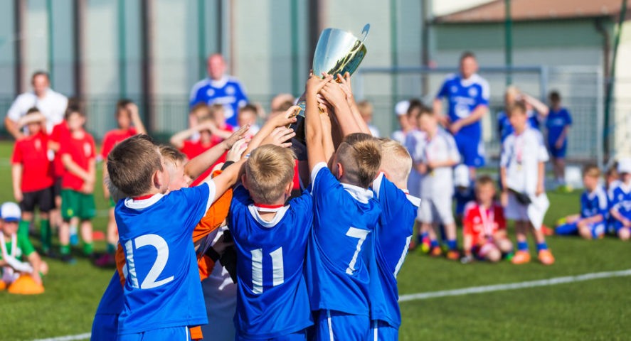 Kids holding soccer trophy celebration